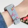 Light blue denim style vegan leather apple watch strap for women with embroidered cherries and pink bows.
