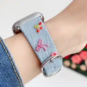 Light blue denim style vegan leather apple watch strap for women with embroidered cherries and pink bows.