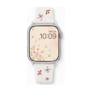 Slim vegan leather Apple Watch band with white linen texture, featuring detailed embroidery of red cherries, pink bows, and wildflowers. Shows silver metal buckle and contrasting olive green leather loops. Perfect gift for her.