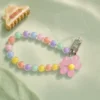 Durable pastel daisy pink beaded phone strap for women featuring a lightweight acrylic bead chain and a silver metal clasp.