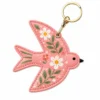 Coral pink vegan leather AirTag case shaped like a bird with white daisies and gold keyring clip.