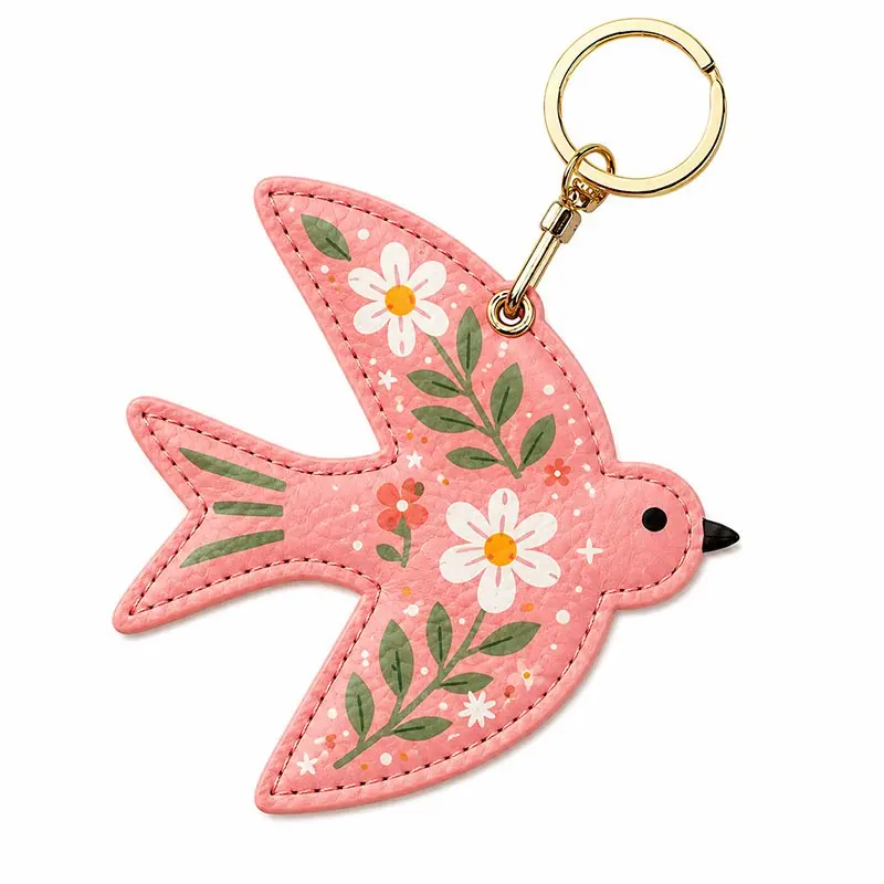 Coral pink vegan leather AirTag case shaped like a bird with white daisies and gold keyring clip.