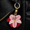 Close up of layered yellow and ivory petals with sage green leaf stitching on vegan leather AirTag case