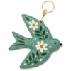 Sage green vegan leather AirTag case shaped like a bird with white daisies and gold keyring clip.