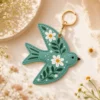 Sage green AirTag keyring on a handbag — cute vegan leather bird bag charm for women.
