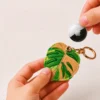 Caramel monstera leaf vegan leather AirTag case in tan and green with gold keyring, cute AirTag holder for women