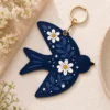 Navy floral AirTag keychain clipped to a handbag — vegan leather bird bag charm and gift for her.