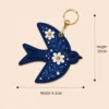 Close up of navy pebbled vegan leather with white daisy and blue leaf design on a bird bag charm.