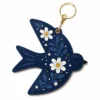 Navy blue vegan leather AirTag case shaped like a bird with white daisies and gold keyring clip.