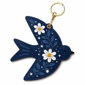 Navy blue vegan leather AirTag case shaped like a bird with white daisies and gold keyring clip.
