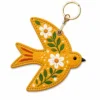 Mustard yellow vegan leather AirTag case shaped like a bird with white daisies and gold keyring clip