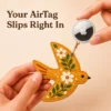 Mustard yellow vegan leather AirTag case shaped like a bird with white daisies and gold keyring clip