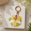 Vegan leather AirTag case in yellow and ivory vintage lily design with gold keyring, cute AirTag holder for women