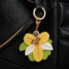 Vegan leather AirTag case in yellow and ivory vintage lily design with gold keyring, cute AirTag holder for women